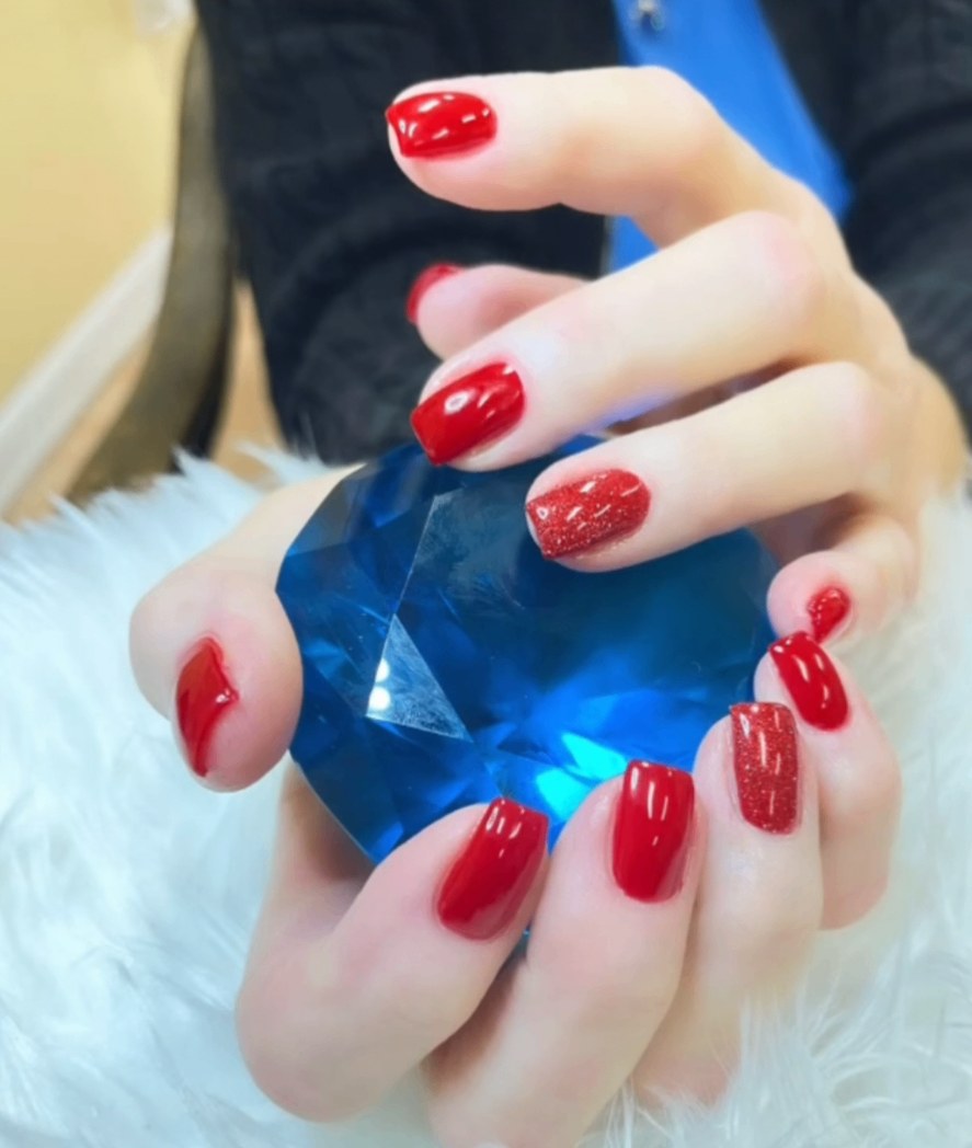 Glossy red square nails with red glitter accents